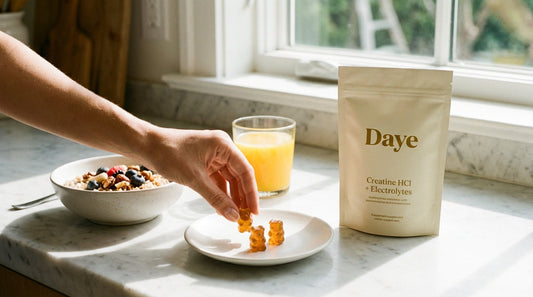 Hand reaching for creatine gummies on plate next to breakfast and Daye pouch