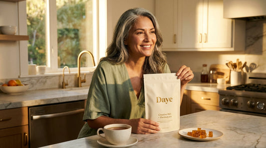 Woman in her 50s holding Daye creatine pouch in kitchen